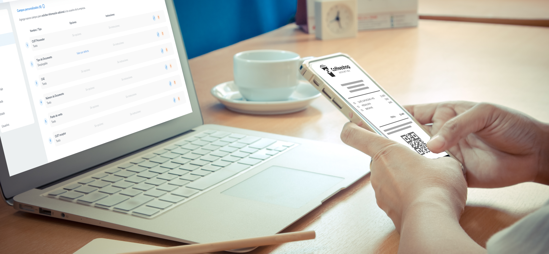 Persona revisando una factura en su teléfono móvil mientras trabaja en una computadora portátil. En la pantalla del laptop se muestra una interfaz con opciones de configuración relacionadas con CUIT y documentos fiscales.