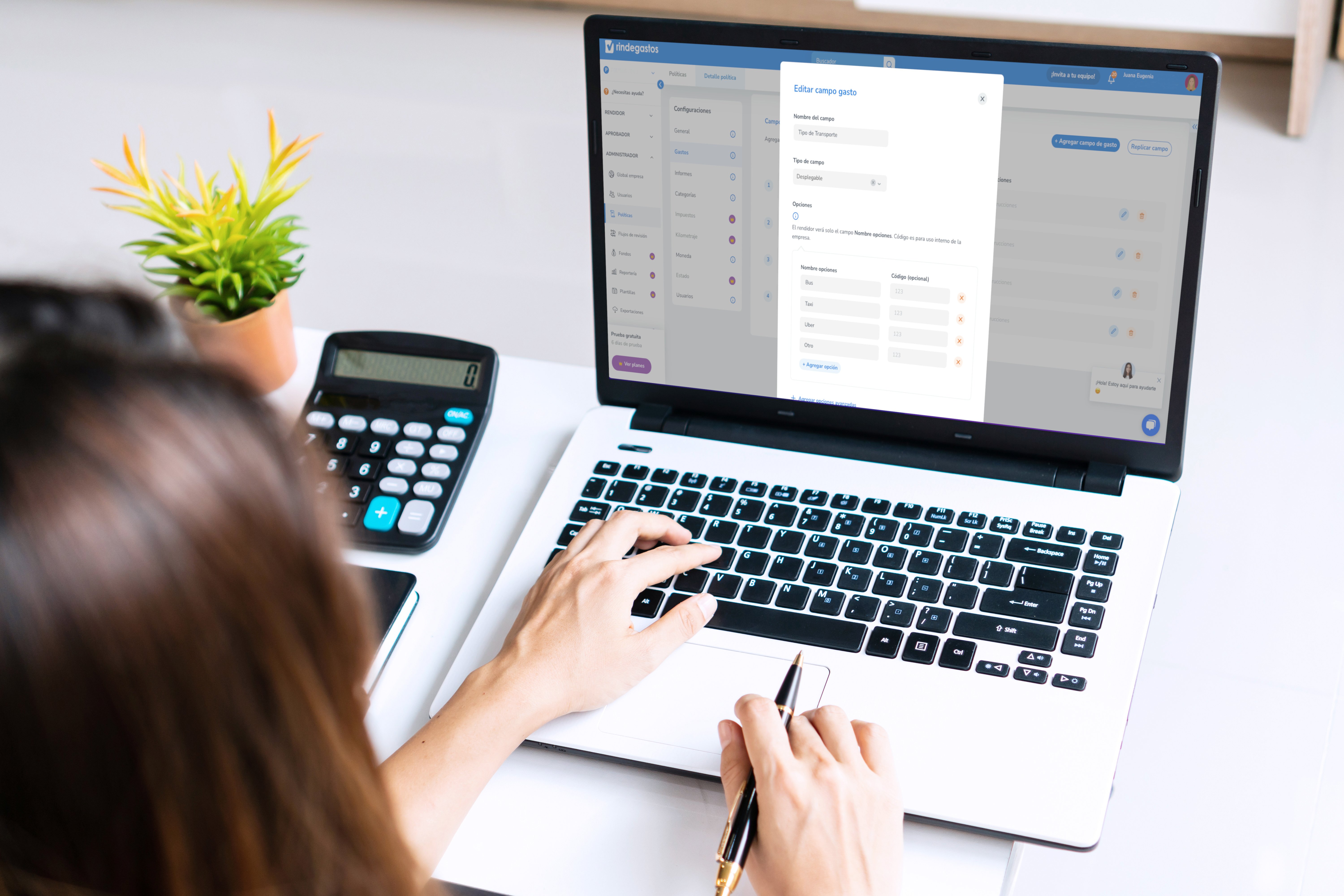 Mujer revisando reportes financieros y configurando datos en laptop con apoyo de calculadora. Gestión precisa de gastos empresariales.